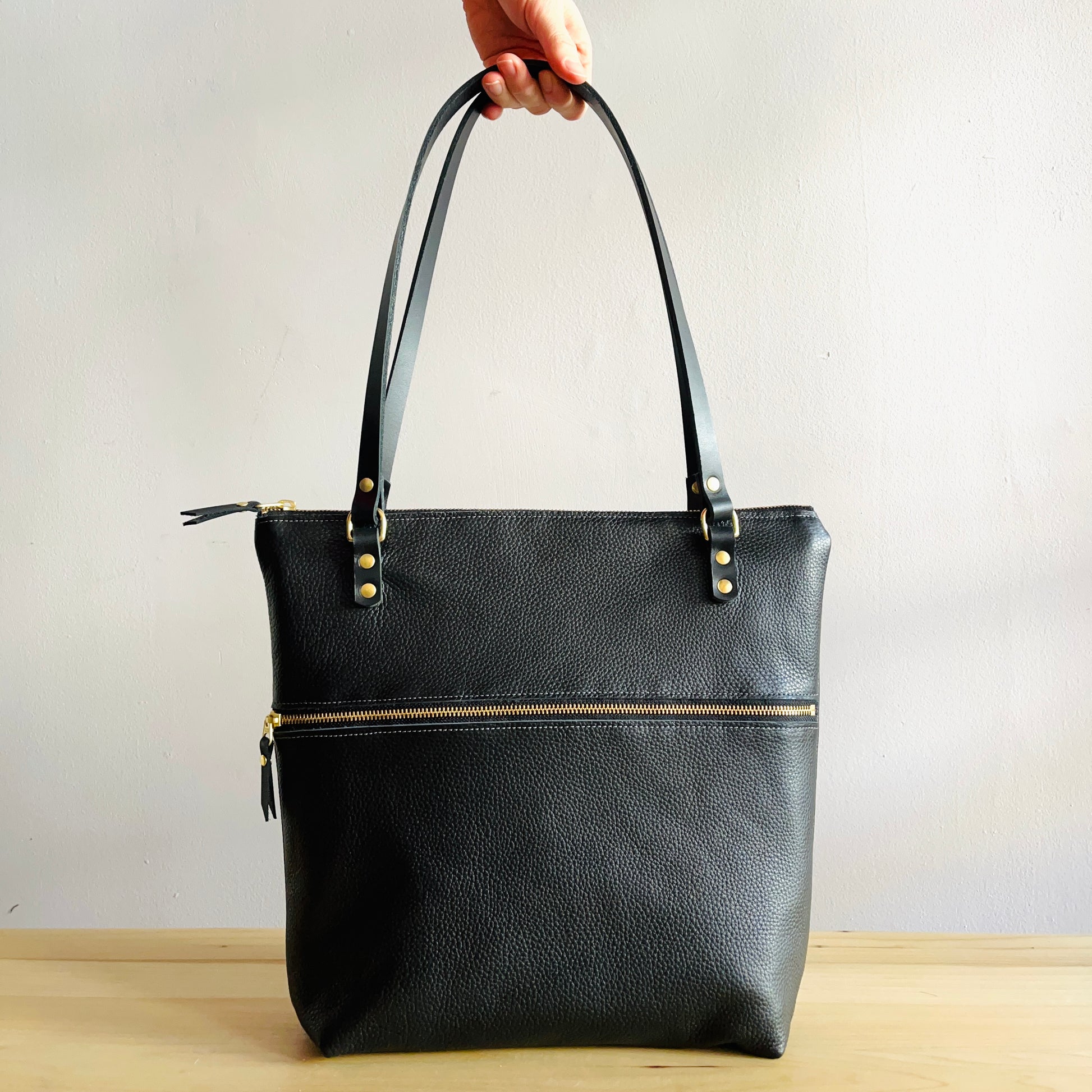 Black leather shoulder bag with zippers by Suzanne Faris
